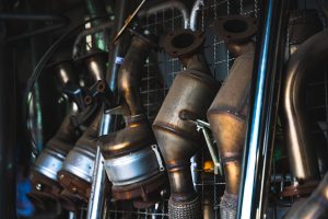 row of catalytic converters hanging neatly on an iron mesh display