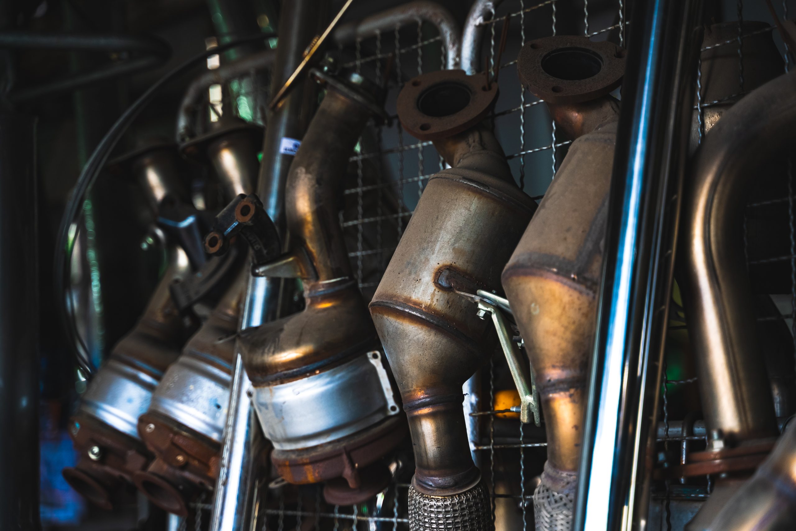 row of catalytic converters hanging neatly on an iron mesh display